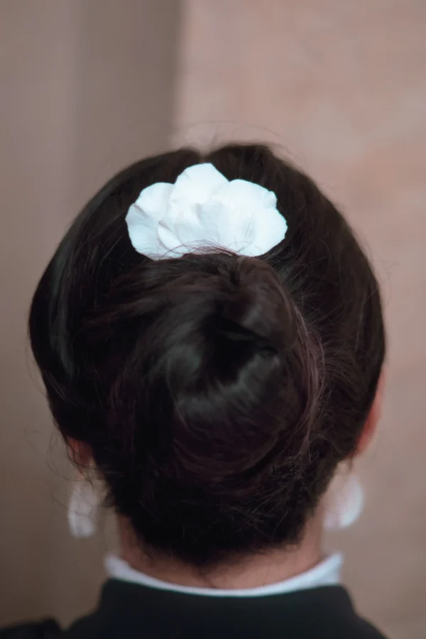 Peigne pétales blancs en porcelaine porté au dessus d'un chignon. Accessoire cheveux de cérémonie.