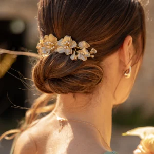 Peigne Mélissa long orné de fleurs or clair et perles nacrées sur chignon bas de mariée
