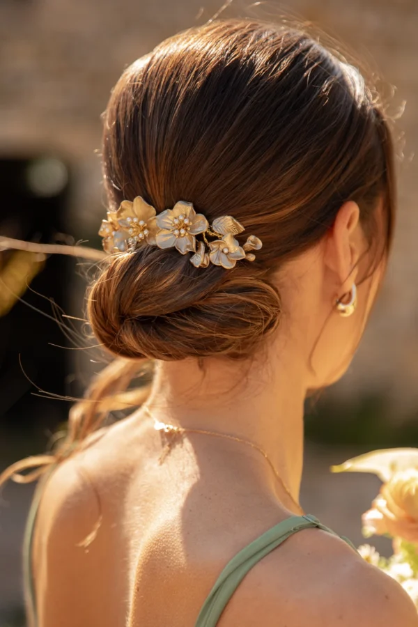 Peigne Mélissa long orné de fleurs or clair et perles nacrées sur chignon bas de mariée