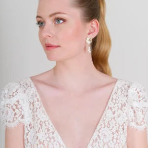 Mariée naturelle. Cheveux tiré et plaqués avec queue de cheveux élégante. Boucles d'oreilles plaqué or et perles d'eau douce bohèmes. Robe de mariée en dentelle