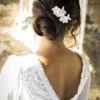 Mariée brune robe bohème dos en V. coiffure chignon bas avec peigne à cheveux fleurs blanches.