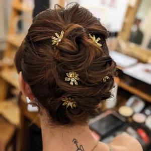 Coiffure chignon flou de mariée avec insertion de pics à chignon en forme de fleurs de perles. Accessoire coiffure luxe