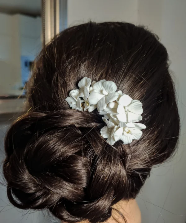 Coiffure chignon mariage Peigne fleurs porcelaine sur le côté du chignon. Épingle chignon mariage