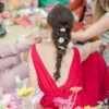 Coiffure bohème. Longue tresse. Robe rouge dos nu sur un tapis de fleurs colorées.
