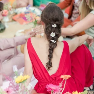 Coiffure bohème. Longue tresse. Robe rouge dos nu sur un tapis de fleurs colorées.