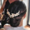 Coiffure de mariage. Grand peigne de fleurs blanches sur chignon bas. Accessoire cheveux de forme V.