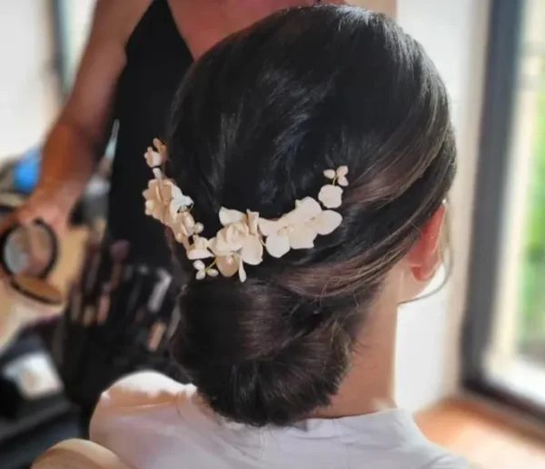 Coiffure de mariage. Grand peigne de fleurs blanches sur chignon bas. Accessoire cheveux de forme V.