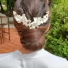 Coiffure de mariage. Grand peigne de fleurs blanches sur chignon bas. Accessoire cheveux de forme V.