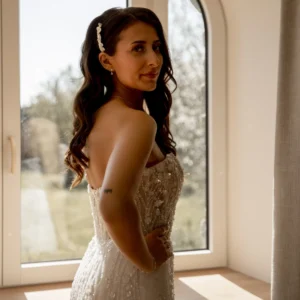 Mariée cheveux long bruns. Cheveux relevés sur un côté fixés par peigne de mariée orné de pétales de porcelaine froide.