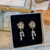Boucles d'oreilles ALBANE dans leur écrin : puce soleil dorée à l'or fin et perles d'eau douce naturelles pendantes, by Marguerite