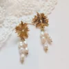 ALBANE à plat sur une dentelle : puces soleil dorées et grappes de perles d'eau douce