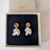 CHLOÉ dans leur écrin noir, vue de dessus : pétales blancs pendants et puces dorées