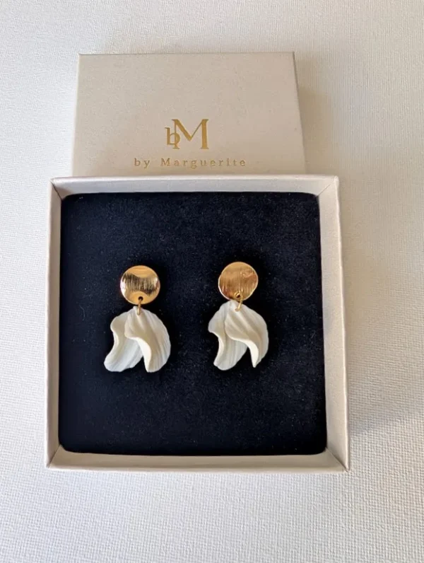 Boucles d'oreilles CHLOÉ 3 <p>Sous une puce en or brossé, les pétales de porcelaine froide de Chloé bougent librement. Des boucles d'oreilles discrètes, pensées pour un mariage civil ou une tenue épurée.</p><ul><li>Faites main dans mon atelier du Pays Basque</li><li>Puce en plaqué or 18k brossé, pétales en porcelaine froide</li><li>Environ 3,3 cm · 2 g</li></ul> CHLOÉ dans leur écrin noir, vue de dessus : pétales blancs pendants et puces dorées