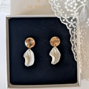 Boucles d'oreilles mariage CHLOÉ dans leur écrin près d'une dentelle : pétales blancs sous une puce en or brossé, by Marguerite
