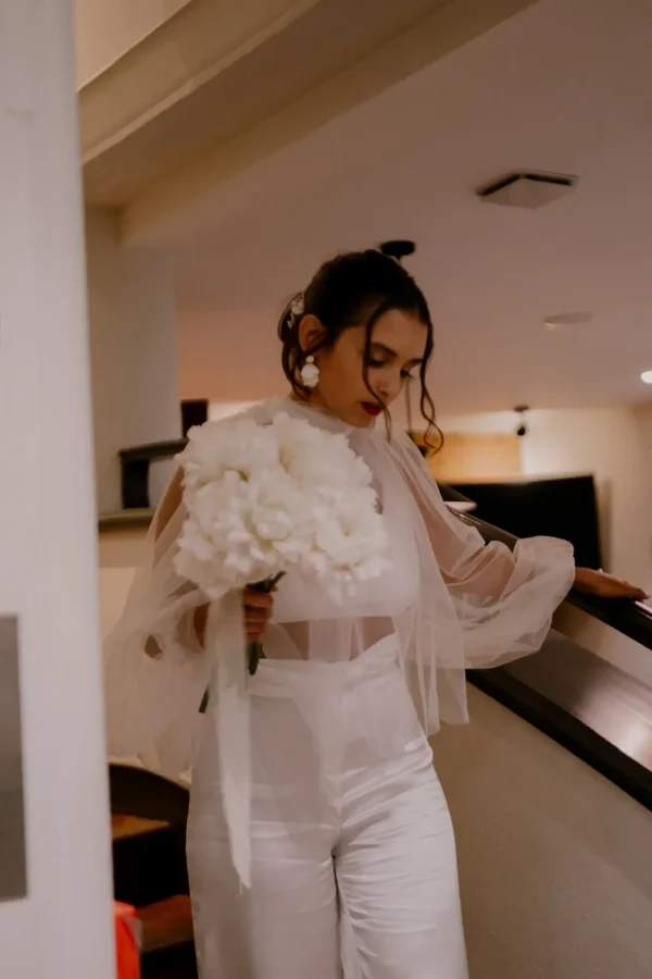 Mariée tenue pantalon blanc et haut manches bouffantes. Boucles d'oreilles pendantes blanches