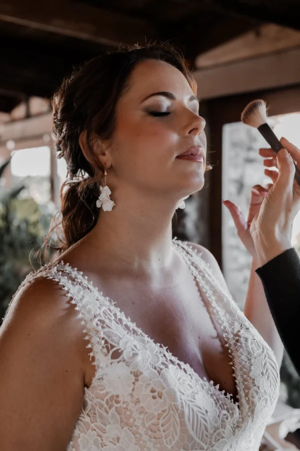 Maquillage de la mariée. Robe dentelle encolure V. Boucles d'oreilles mariage pendantes. Bijou de mariage argenté