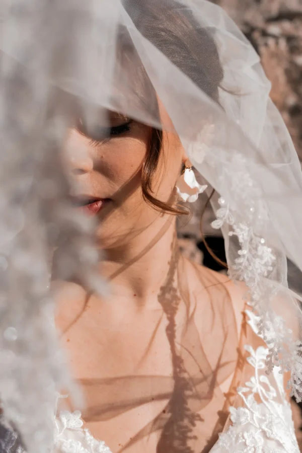 Mariée avec voile ornée de petites fleurs. Bijoux mariage fleurs