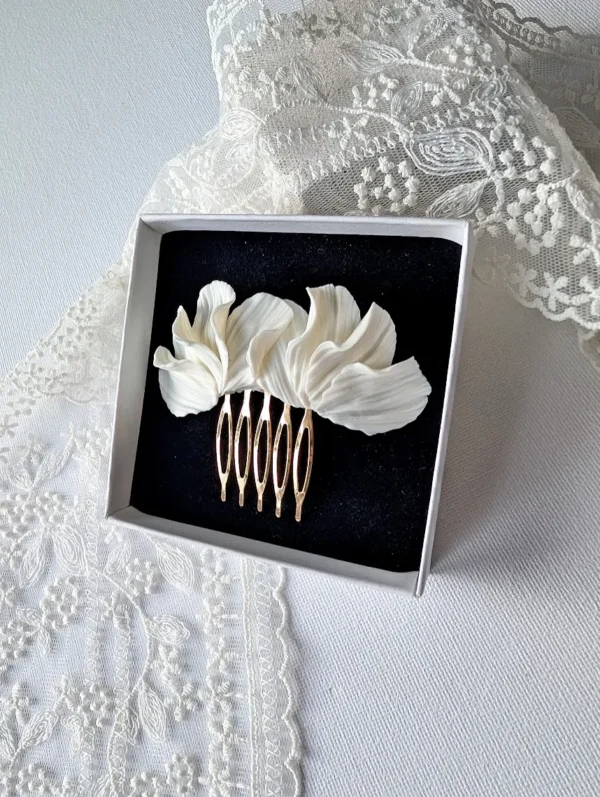 Peigne MARIA 3 <p>MARIA, c'est une branche de pétales blancs en porcelaine froide, longue d'environ 8 cm, montée sur un peigne doré. Ce peigne pétales blancs porcelaine se pose aussi bien sur le côté d'un chignon que sur une demi-coiffure.</p><ul><li>Fait main dans mon atelier du Pays Basque</li><li>Pétales en porcelaine froide, peigne en laiton doré</li><li>Ornement d'environ 8 × 3 cm</li></ul> MARIA dans son écrin noir posé sur une dentelle, vue de biais