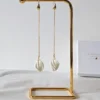 Support boucles d'oreilles métal doré et boucles d'oreilles pendantes longues mariage.