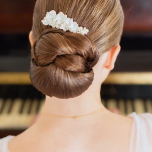 Coiffure mariage minimaliste tendance. Chignon bas travaillé et peigne de porcelaine et perles