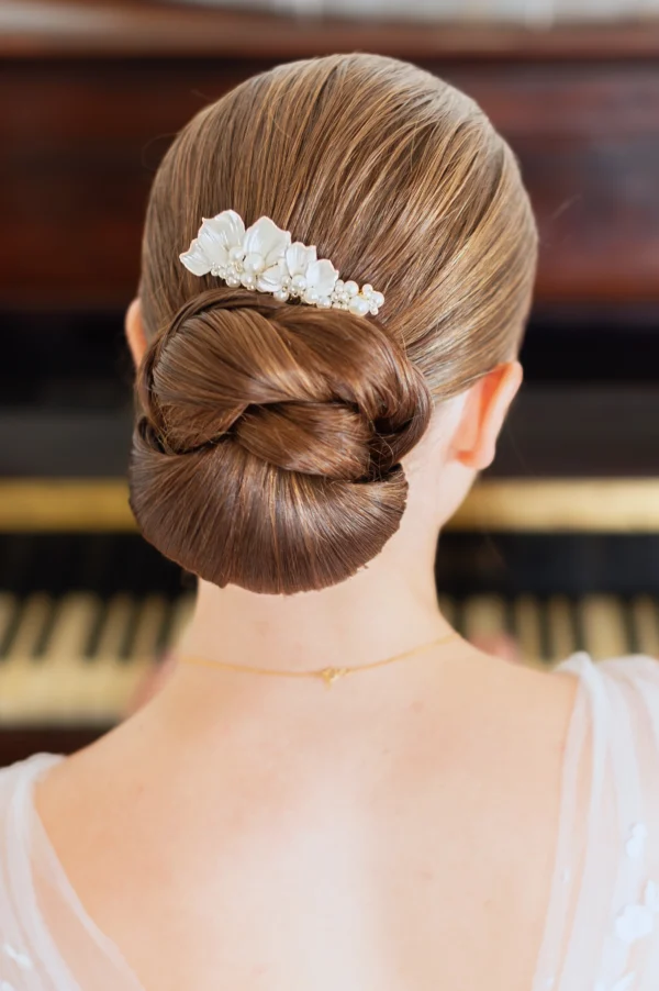 Coiffure mariage minimaliste tendance. Chignon bas travaillé et peigne de porcelaine et perles