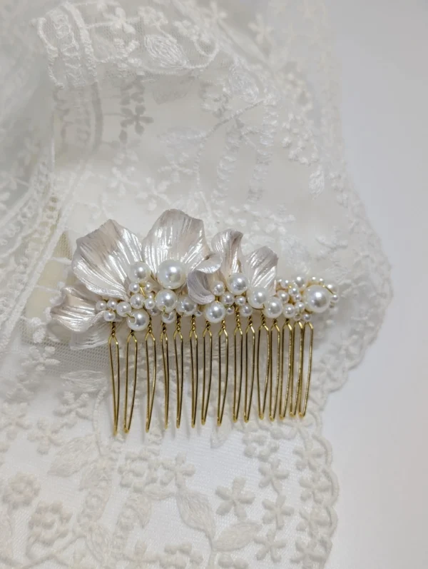 Peigne de mariée pétales nacrés et perles ivoire posé sur le voile de la mariée