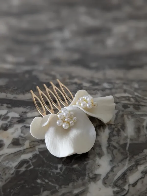 Barrette de mariage minimaliste chic posé à plat. La barette à cheveux est ornée de pétales de porcelaine façonnés main et orné dans son coeur d'un groupe de perles de couleur ivoire