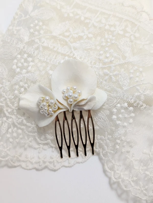 Petit peigne mariage élégante en porcelaine et perles ivoire posé sur un voile de mariée