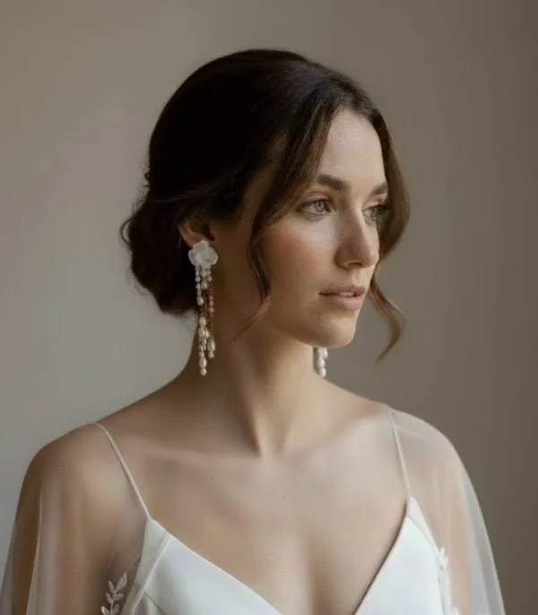 Boucles d'oreilles LÉONIE 2 <p>Léonie réunit mes deux matières préférées, la porcelaine et la perle. Une fleur de porcelaine froide au lobe, puis une cascade de perles d’eau douce sur de fines chaînes, pour des boucles d’oreilles de mariée pleines de mouvement.</p><ul><li>Faites main dans mon atelier du Pays Basque</li><li>Fleur en porcelaine froide, perles d’eau douce, tige et chaînes gold filled 14k</li><li>Fleur de 2,2 cm · environ 7,5 cm de long</li></ul> Mariée brune avec chignon bas. Bijou de la mariée boucle d oreille mariage perles et porcelaine