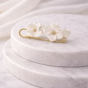 Attache-traîne DIANE posée à l'horizontale : fleurs en porcelaine froide sur une épingle dorée