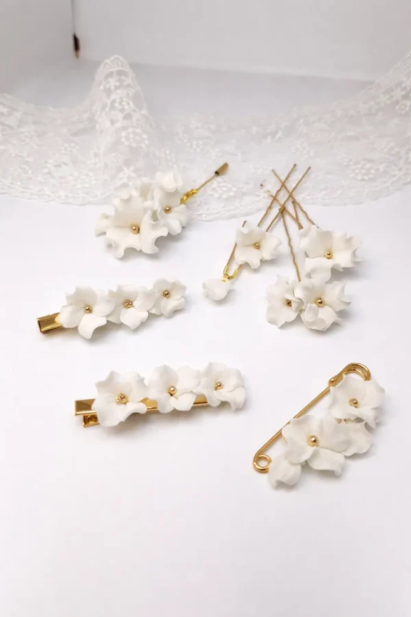 Attache-traîne DIANE 3 <p>Une épingle dorée et quelques fleurs blanches en porcelaine froide : DIANE est une attache-traîne mariée qui relève la traîne après la cérémonie, pour danser librement. Elle sert ensuite de broche ou d'attache de boléro.</p><ul><li>Fait main au Pays basque, en France</li><li>Fleurs en porcelaine froide, épingle en laiton</li><li>Longueur : 5 cm</li></ul> Ligne DIANE : attache-traîne, barrettes, épingles et boutonnière aux fleurs blanches en porcelaine froide