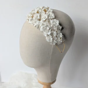 Bandeau NATALIA sur une tête de présentation en lin : fleurs blanches en porcelaine froide serrées sur toute la largeur