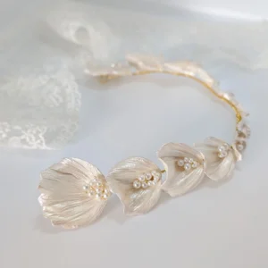 Demi-couronne VIVIENNE posée sur une dentelle : pétales de porcelaine nacrée et perles le long d'un fil doré