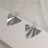 Boucles d'oreilles VICTORIA argentées sur un fond clair : éventails plissés en métal argenté et cristaux