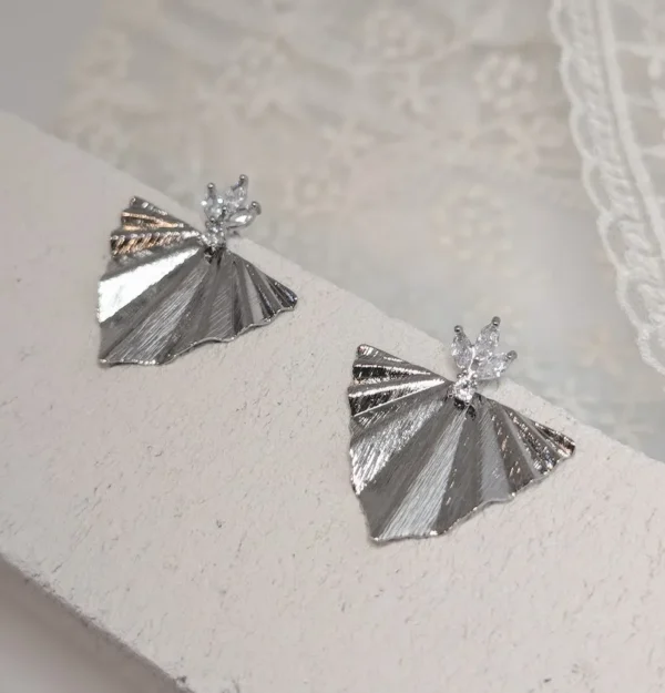 Boucles d'oreilles VICTORIA argentées sur un fond clair : éventails plissés en métal argenté et cristaux