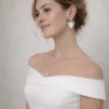 Mariée en robe à épaules dénudées et chignon bas portant les boucles d'oreilles VICTORIA argentées