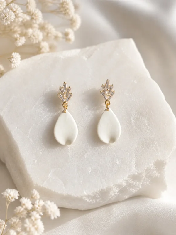 Boucles d'oreilles KATE 3 <p>Kate est une goutte de porcelaine froide, lisse et légèrement recourbée, sous une puce sertie de zirconium. Ces boucles d'oreilles ont une tige adaptée aux oreilles sensibles.</p><ul><li>Faites main dans mon atelier du Pays Basque</li><li>Puce plaquée or 16k sertie de zirconium, tige en acier chirurgical 316</li><li>Longueur totale : environ 4 cm · 1,7 g</li></ul> Boucles d’oreilles Kate en porcelaine froide posées sur une pierre blanche texturée, avec détails dorés et cristaux, dans une ambiance lumineuse et épurée.