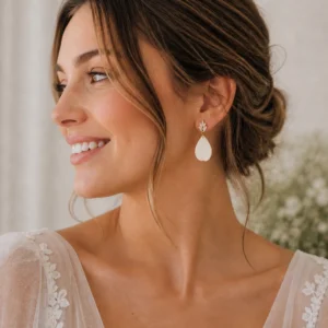 Boucles d’oreilles mariage Kate portées par une femme, avec goutte en porcelaine et cristaux, apportant une touche élégante et lumineuse à une tenue de mariée.