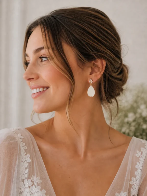 Boucles d'oreilles KATE 2 <p>Kate est une goutte de porcelaine froide, lisse et légèrement recourbée, sous une puce sertie de zirconium. Ces boucles d'oreilles ont une tige adaptée aux oreilles sensibles.</p><ul><li>Faites main dans mon atelier du Pays Basque</li><li>Puce plaquée or 16k sertie de zirconium, tige en acier chirurgical 316</li><li>Longueur totale : environ 4 cm · 1,7 g</li></ul> Boucles d’oreilles mariage Kate portées par une femme, avec goutte en porcelaine et cristaux, apportant une touche élégante et lumineuse à une tenue de mariée.