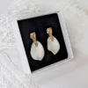 Boucles d'oreilles ROXANNE dans leur écrin noir, posé sur une dentelle