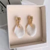 ROXANNE dans un coffret beige ouvert : pétales blancs légèrement structurés et puces dorées texturées