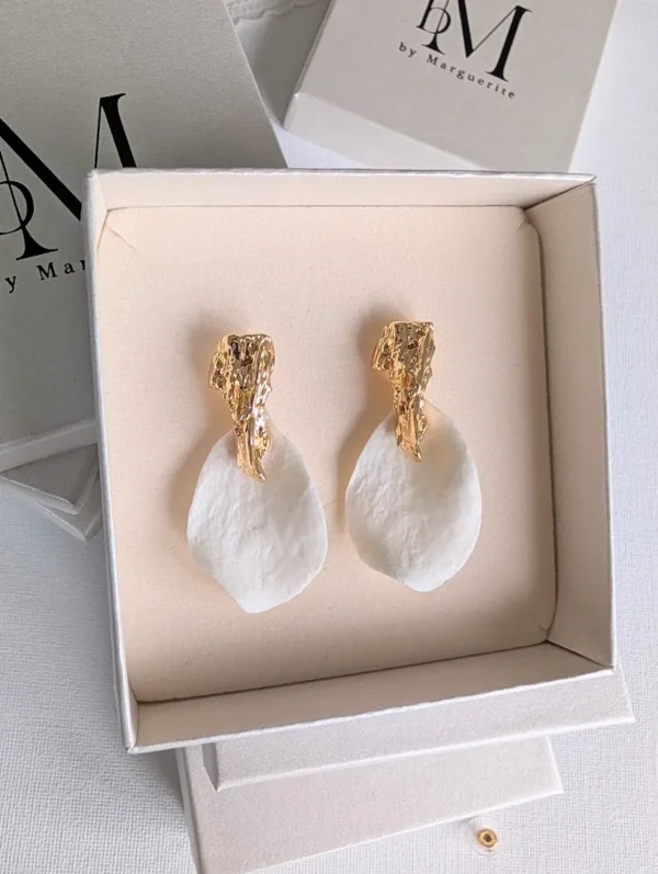 ROXANNE dans un coffret beige ouvert : pétales blancs légèrement structurés et puces dorées texturées