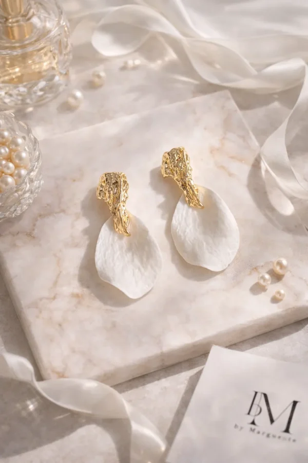 Boucles d'oreilles mariage ROXANNE : pétales blancs en porcelaine froide sous une puce dorée martelée, sur un marbre clair, by Marguerite