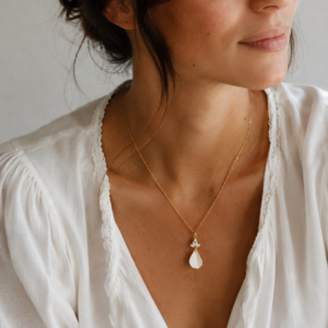 Collier NOÉMIE porté : pétale blanc en porcelaine froide sur une chaîne fine dorée, encolure en V