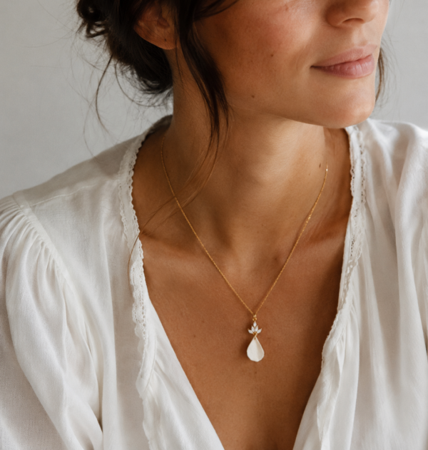 Collier NOÉMIE porté : pétale blanc en porcelaine froide sur une chaîne fine dorée, encolure en V