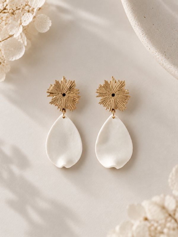 Boucles d'oreilles ZÉLIE 1 <p>Zélie associe une puce dorée en forme de soleil et un pétale blanc en porcelaine froide, à la forme libre. Des boucles d'oreilles lumineuses et légères, loin du bijou standardisé.</p><ul><li>Faites main dans mon atelier du Pays Basque</li><li>Puce soleil en laiton plaqué or 18k, pétale en porcelaine froide</li><li>Pétale de 2 × 3,3 cm · 1,8 g</li></ul> Boucles d’oreilles Zélie dorées avec puce en forme de soleil et pétale blanc en porcelaine froide, création artisanale pour mariage.