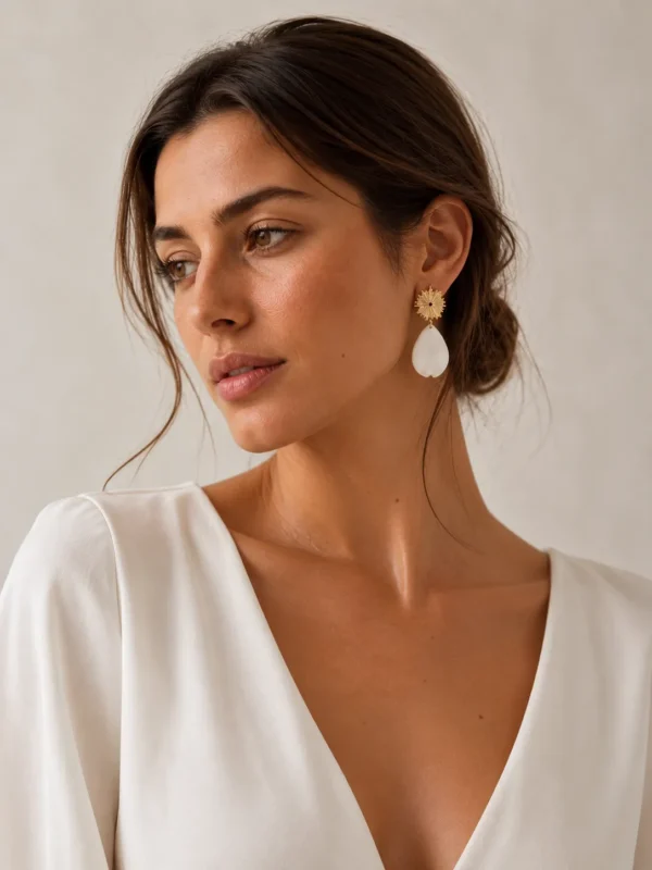 Boucles d'oreilles ZÉLIE 2 <p>Zélie associe une puce dorée en forme de soleil et un pétale blanc en porcelaine froide, à la forme libre. Des boucles d'oreilles lumineuses et légères, loin du bijou standardisé.</p><ul><li>Faites main dans mon atelier du Pays Basque</li><li>Puce soleil en laiton plaqué or 18k, pétale en porcelaine froide</li><li>Pétale de 2 × 3,3 cm · 1,8 g</li></ul> Boucles d’oreilles mariage Zélie dorées et blanches portées par une femme, avec puce soleil et pétale en porcelaine froide.