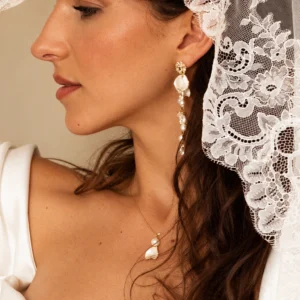 Mariée de profil sous un voile de dentelle portant les boucles d'oreilles pendantes ADÉLAÏDE, by Marguerite