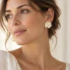 Puces d'oreilles fleur ALMA portées avec une blouse en lin et un chignon flou, des boucles légères à porter tous les jours