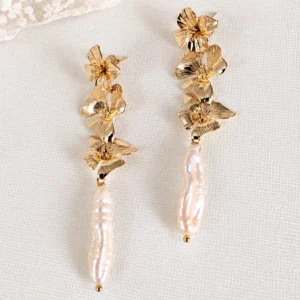 Boucles d'oreilles NORA : trois fleurs dorées et longue perle d'eau douce naturelle, sur fond blanc, by Marguerite